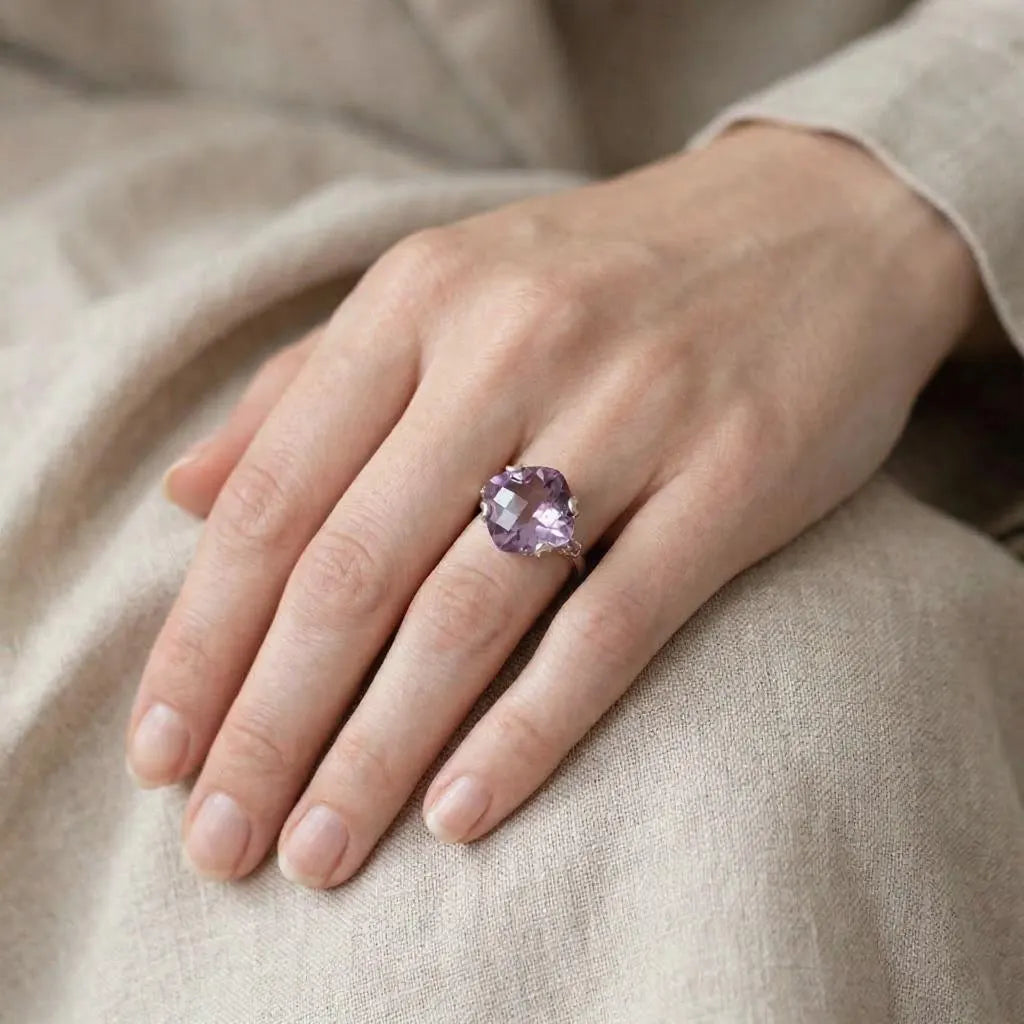 Hand wearing a ring with a purple gemstone