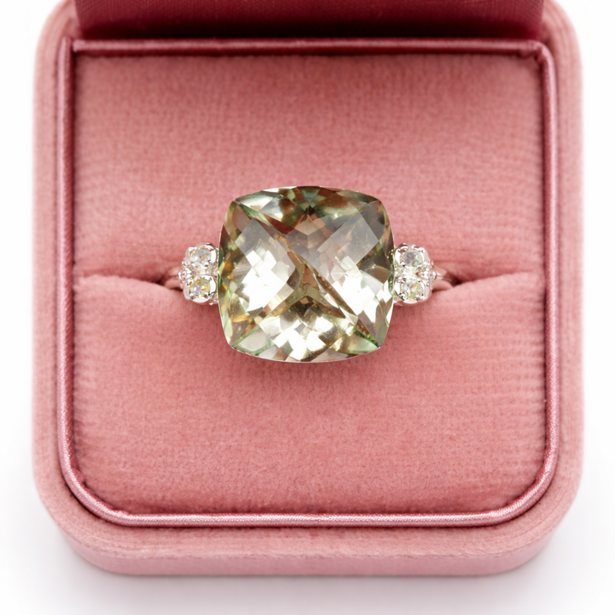 Ring with a large green gemstone and smaller stones on a pink cushion